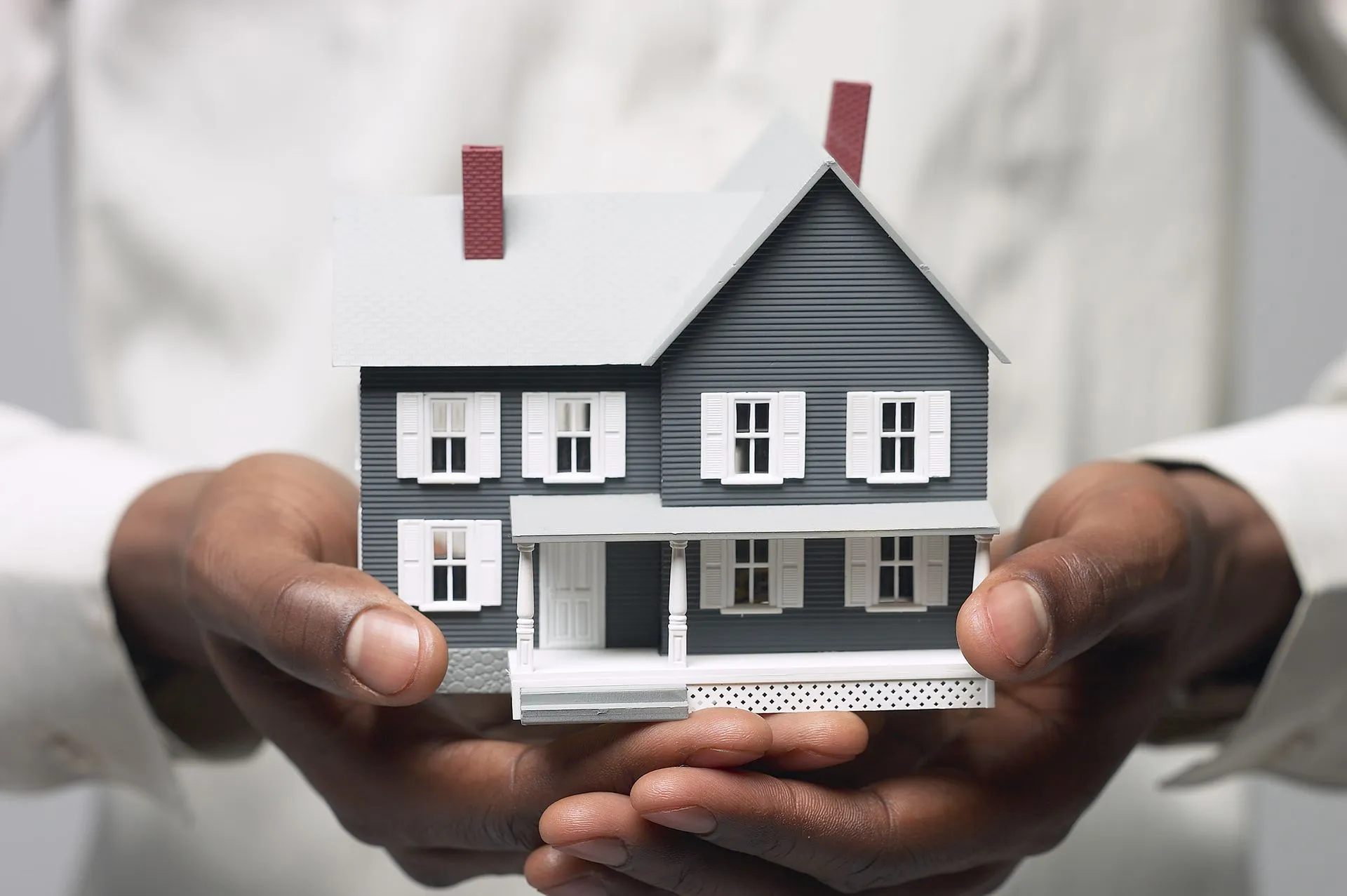 Hands holding a miniature house, symbolizing homeownership.